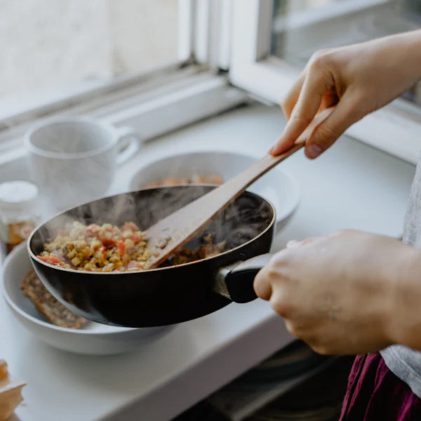 Hands stirring a pan of food on the stove