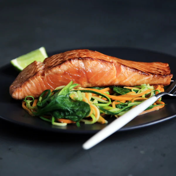 Grilled salmon with greens on a dark plate